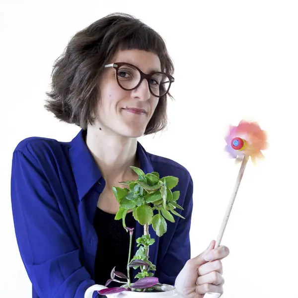 Portrait de Ludivine Thiburs, un moulin à vent coloré et une plante à la main